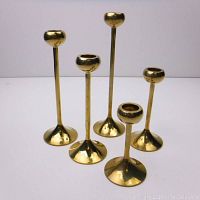Group photo of five brass candlesticks showing varying heights and polished brass finish.