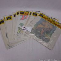 Group view of 12 sealed Rat's Hole hot iron-on transfer packages from the 1970s arranged overlapping on a white surface.