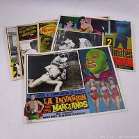 Five vintage Mexican movie lobby cards fanned out showing a variety of graphic and black & white scenes and colorful titles from films.