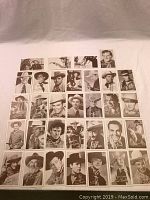 Complete set of 32 black and white penny arcade cards laid out in a grid on a white background, showing portraits of Western stars with various facial expressions and costumes.