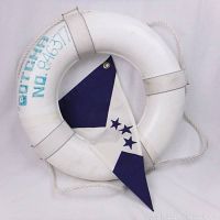 Life preserver ring with rope, white with blue stenciled numbers and letters, partially showing the nautical flag tucked inside ring