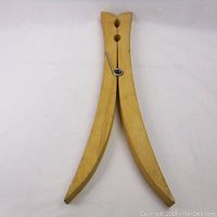 Front angled view of the large wooden clothespin wall ornament showing the curved wooden arms and metal spring mechanism.