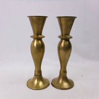 Pair of brass candlesticks shown from front, highlighting overall shape and condition.