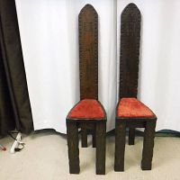 Two rustic gothic style chairs in dark wood with tall narrow backs and red velvet studded seats, shown side by side from the front.