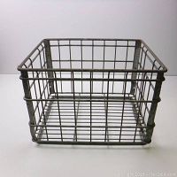 Front and side view of a metal wire milk crate showing grid wire construction and reinforced edges.