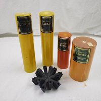 Full view of four Lenox candles in yellow, orange, and vanilla scent labeling alongside a black metal tapered candle holder.