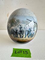 Front view of large glass egg showing elephant herd imagery