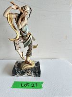 Front view of ceramic flute-playing figure on marble base
