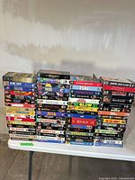 Wide view showing four tall stacks of VHS tapes on a folding table