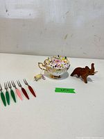 Full lot view showing forks, teacup pincushion, wooden elephant