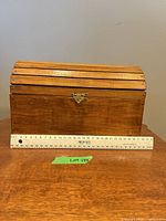 Front view of small wooden chest with ruler for scale