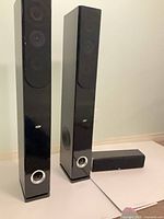 Pair of black tower speakers with center channel in front
