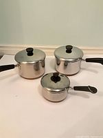 Three saucepans with lids, exterior view