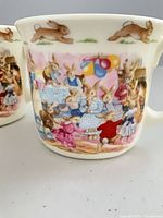Front view of Royal Doulton Bunnykins mug showing rabbit birthday party illustration