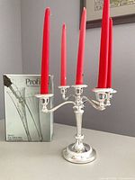 Candelabra with five red candles beside boxed champagne glasses