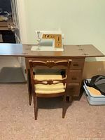 Cabinet open with sewing machine deployed, chair front