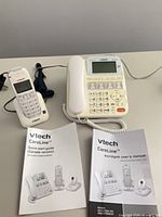 Complete set showing corded base, cordless handset on cradle, two manuals and power adapter cords