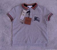 Full front view of grey Burberry kids polo shirt with tags attached