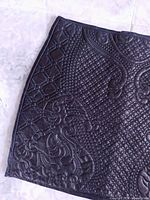 Front view of black faux leather quilted paisley mini skirt