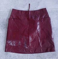 Front view of maroon faux leather skirt showing pockets and overall condition