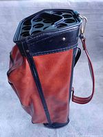 Side view of brown and black faux leather golf bag showing club divider and strap