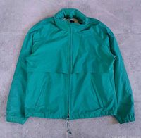 Front view of green Eddie Bauer jacket showing zipper, pockets, drawcord