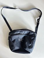 Full view of black Arc’teryx shoulder bag with strap displayed