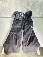 Full view of Helly Hansen black ski pants laid flat
