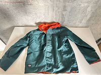 Front view of teal Helly Hansen jacket with hood, laid flat