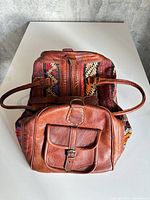 Front view showing leather pocket, handles, textile panels