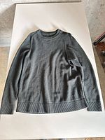 Full view of the dark green Lululemon long sleeve shirt laid flat
