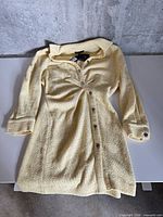 Full view of Maje pale yellow tweed dress laid flat