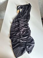 Full view of black ruched dress laid flat