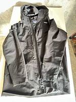 Full view of jacket laid flat showing hood, front zip, pockets, Thermogreen sleeve patch