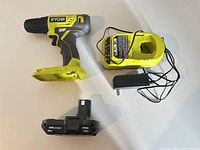 Cordless drill, battery and charger laid out side by side