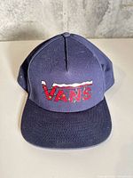 Front view of navy blue Vans cap showing embroidered logo
