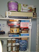 Overall view of shelf with multiple puzzle boxes and tins