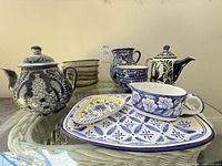 Group shot showing both teapots, pitcher, platter, handled bowl, triangular plate and stack of bowls