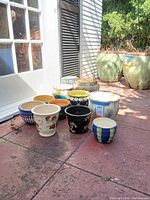 Group of nine assorted ceramic pots on patio