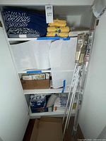 Closet view of towels, boxed curtains, packaged tension poles and rod