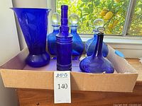 Front view of all cobalt blue glass pieces inside box