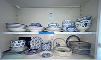 Two shelves showing entire assortment of blue & white plates and bowls