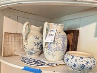 Shelf view showing both pitchers, platter, bowl, decorative tile