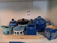 Front view of all ceramic pieces on shelf with ruler