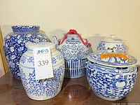 Front view of five blue and white ceramic jars with lids, showing size and pattern differences