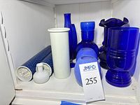 Shelf view of all cobalt blue glass vases, tumblers and white ceramic vases