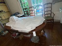 Overall view of table with cloth cover and four ladder-back chairs