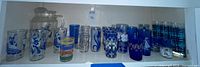 Shelf of assorted blue-themed tumblers and clear pitcher