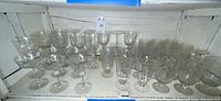 Shelf full of assorted clear Fostoria floral-etched stemware