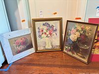 Three framed floral artworks on floor showing overall view